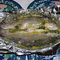 Pstrąg pieczony w masełku z czosnkiem koperkiem i pietruszką