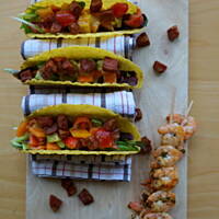 Tacos z salsą z pomidorów, awokado i papryki serwowane z chorizo i grillowanymi krewetkami